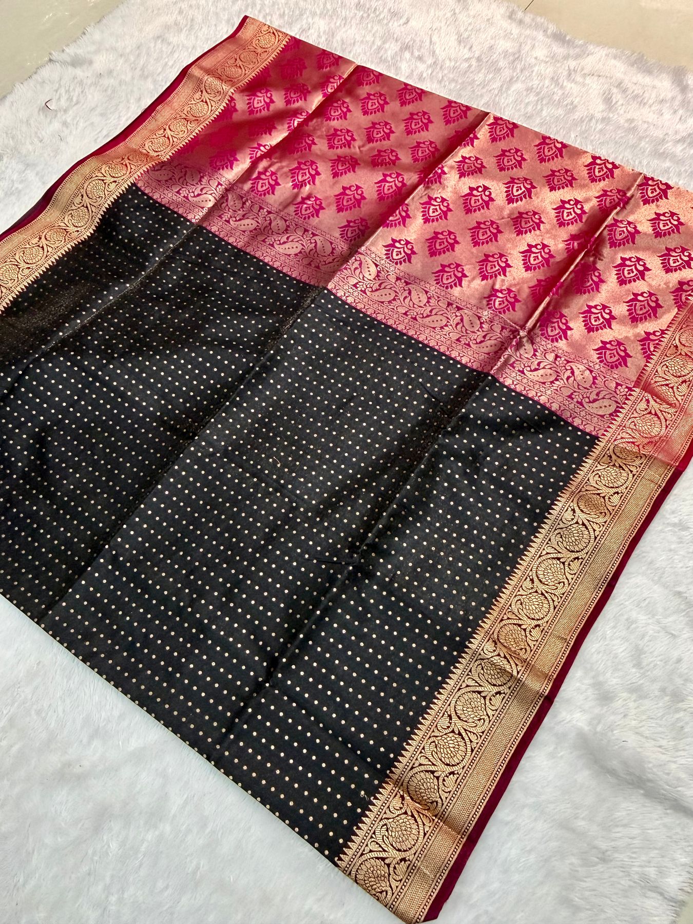 Black banarasi katan silk with a gold zari border, laid out on the counter